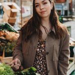 Woman buying fresh produce at an outdoor market in Erfurt, Germany with a basket of vegetables.