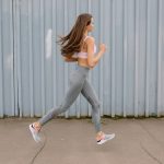 Fit woman running outdoors in activewear with sports bra and leggings. Motion captured at day time.